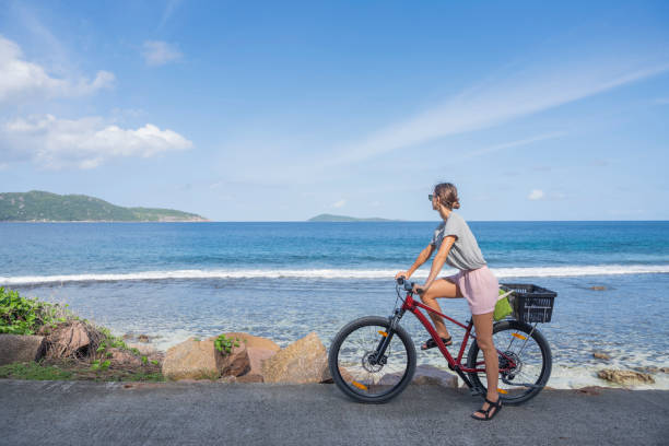 istock Young woman rides bicycle along seaside 2193342039