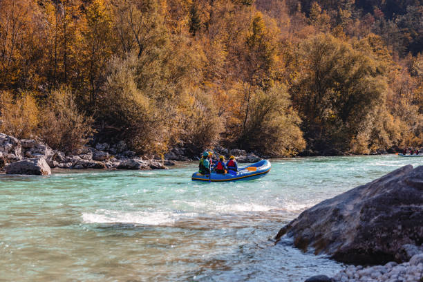 A family in life jackets is rafting down a river with a guide, surrounded by nature.