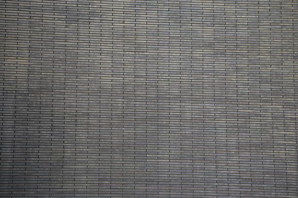 A brick wall with a gray color. The wall is made of bricks and has a rough texture