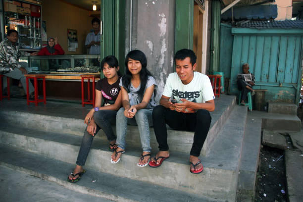 BUKITTINGGI, INDONESIA - July 25, 2010.Three young adults sitting on steps outside a store in Bukittinggi, West Sumatra, Indonesia.