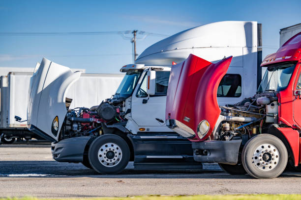 Broken big rig semi trucks with open hoods standing on the industrial parking lot waiting for repair and maintenance specialist stock photo