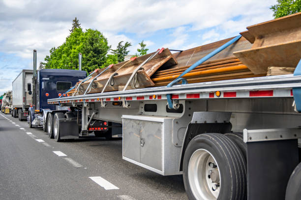 istock Dark blue classic big rig semi truck transporting fastened metal cargo on flat bed semi trailer running on the busy highway road with semi trucks convoy 2193352953