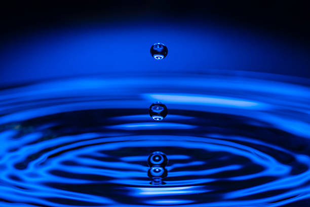 Water drop splashing on the surface of the water in a blue background.