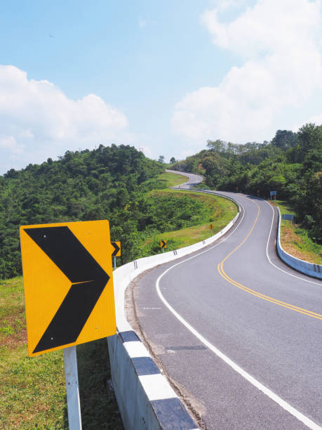istock warning arrow sign on a dangerous curve road across mountain. 2193355431
