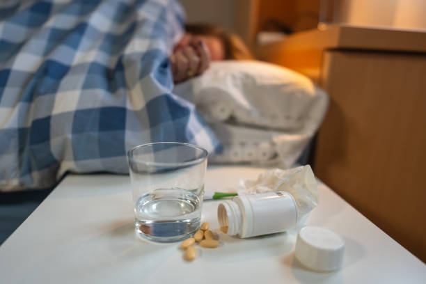 istock Woman lying in bed with flu symptoms and medicine on bedside table. 2193357113
