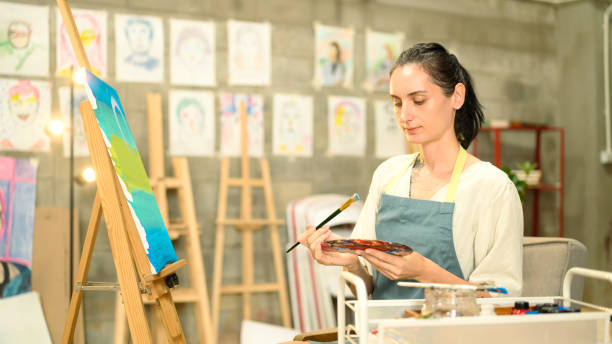istock Creative artist holding paintbrush and palette working on colorful canvas in a bright studio 2193359060