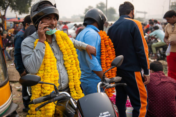 New Delhi, India-November 04, 2021:People carrying marigold flower garlands at the wholesale flower market, as flowers are essential for decoration and offerings in Hindu festivals.