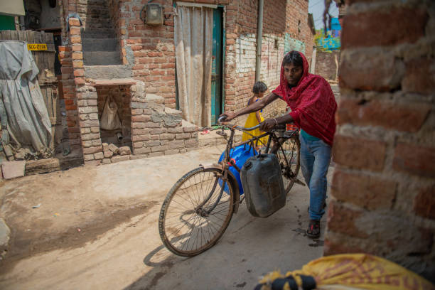 New Delhi, India-April 18,2017: Man holding a bicycle with water containers hanging on it.