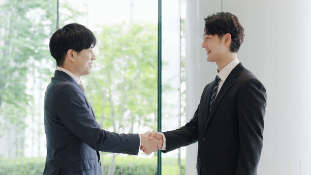 istock Asian businessmen shaking hands in a lobby 2193366333