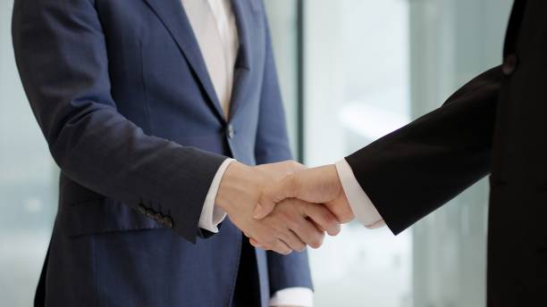 Asian businessmen shaking hands in a lobby stock photo