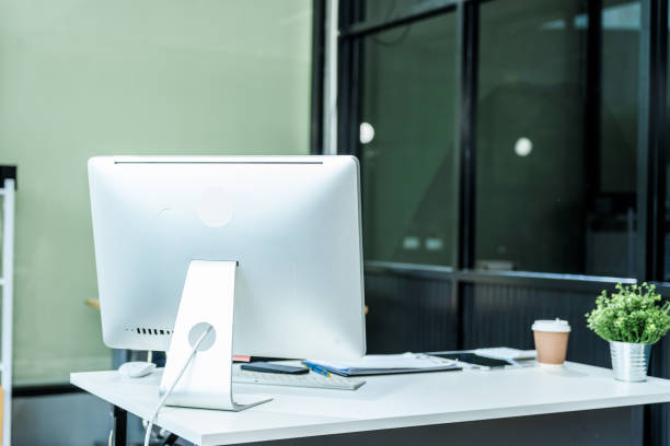 istock A sleek modern desk with a computer and laptop sits empty in a glass office, reflects a contemporary style with no people present, emphasizing a clean, professional environment. 2193367646