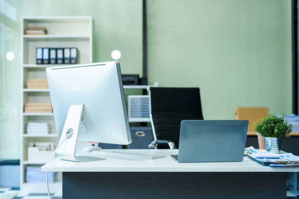 istock A sleek modern desk with a computer and laptop sits empty in a glass office, reflects a contemporary style with no people present, emphasizing a clean, professional environment. 2193367650