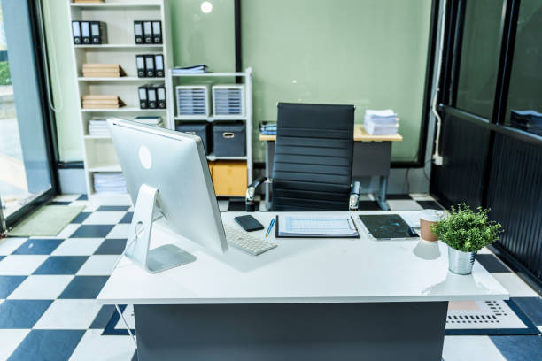 istock A sleek modern desk with a computer and laptop sits empty in a glass office, reflects a contemporary style with no people present, emphasizing a clean, professional environment. 2193367663