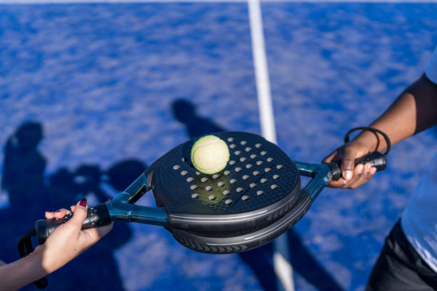 istock Two padel rackets holding a ball on a blue court 2193369286