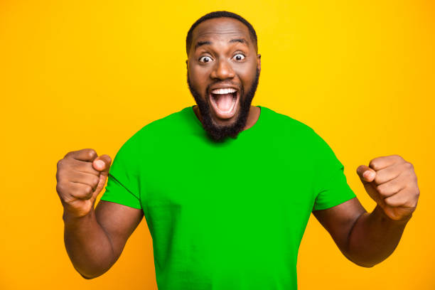 istock Photo of excited crazy black man having possibly won some contests end rejoicing with it while isolated with yellow background 2193376688
