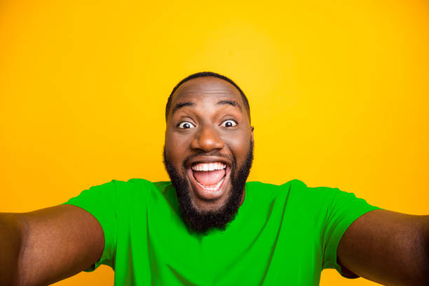 istock Self portrait of rejoicing overjoyed black man playing new camera with face delighted while isolated with yellow background 2193376721