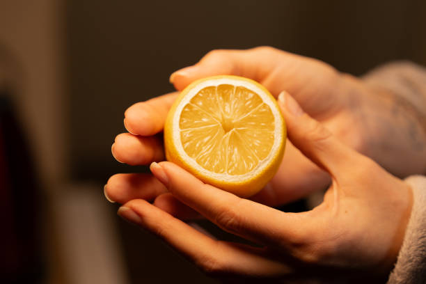 istock Hands holding a fresh lemon slice in a cozy indoor setting during evening light 2193379543