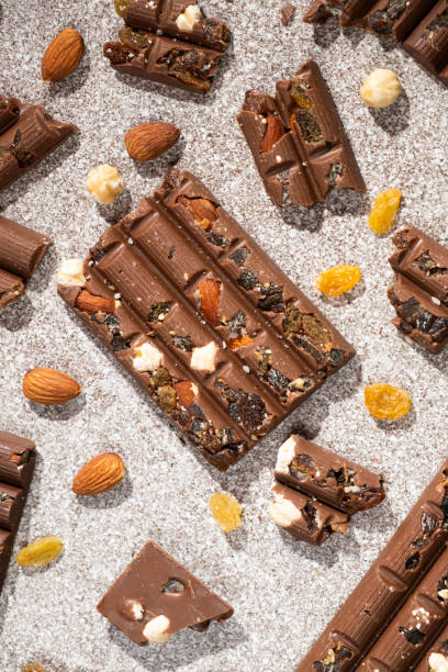 istock Broken chocolate pieces with nuts and raisins on a stone background top view 2193380049