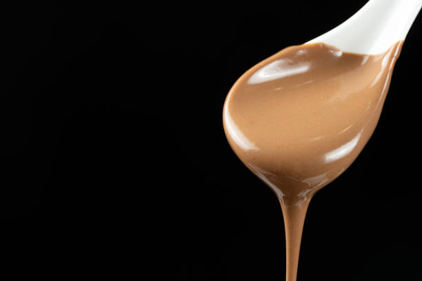 istock Melted milk chocolate poured out of a spoon, copy space for text 2193380086
