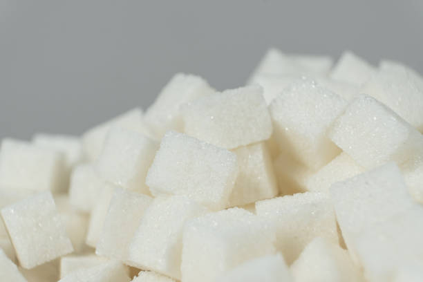white square sugar on a black background , lump sugar in the shape of a square on a black slate