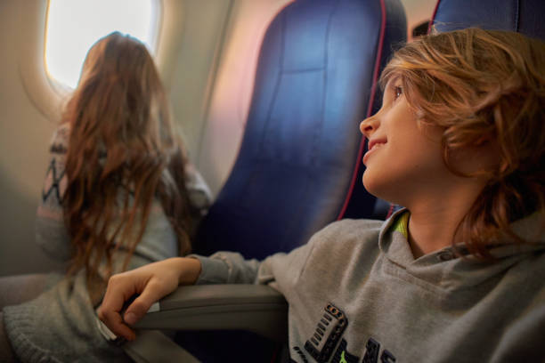 istock Boy and girl looking through the plane window 2193381030