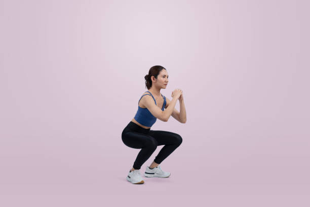 istock Vigorous energetic woman doing exercise with squat on isolated background. 2193382355