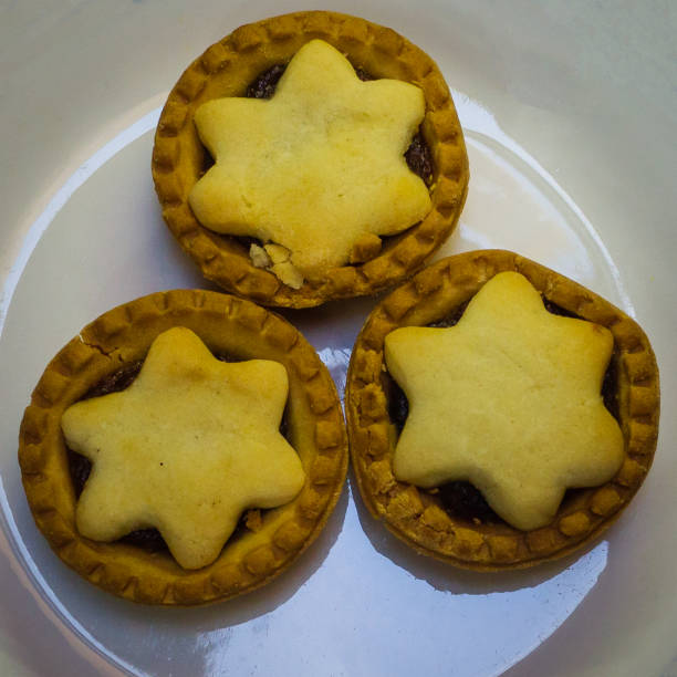Three traditional mince pies with star-shaped tops arranged on a white plate, perfect for festivities and holiday celebrations.