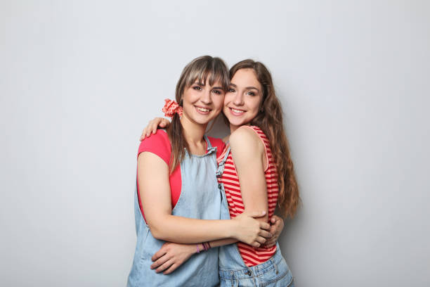 istock Two young woman hugging each other on grey background 2193391081
