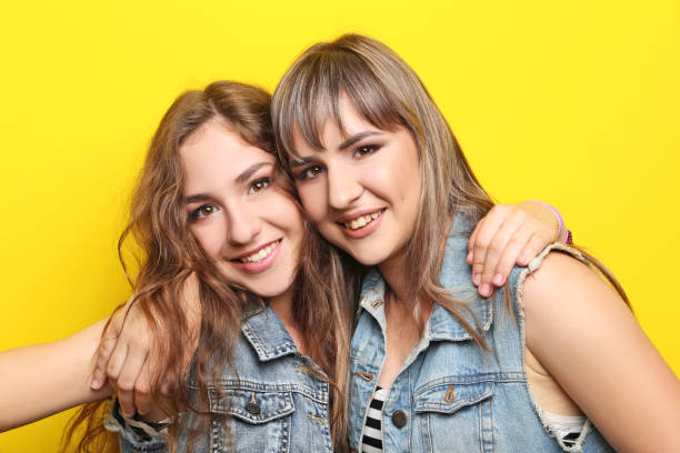 istock Two young woman hugging each other on yellow background 2193391110