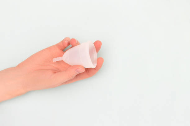 istock Female hand hold white menstrual cup on a blue background. 2193391561