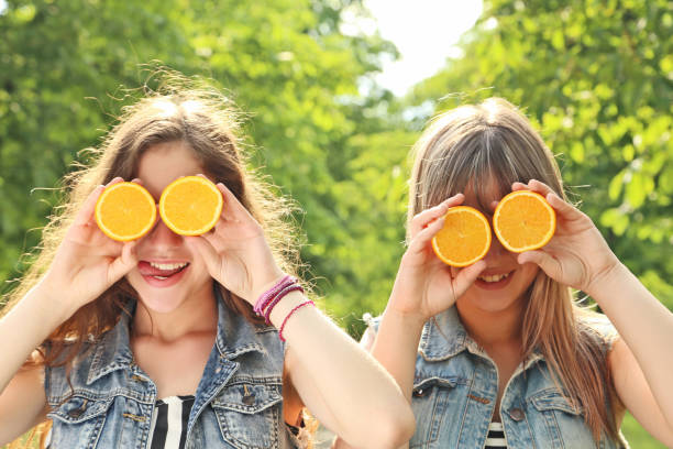 istock Two young woman with orange fruit in the park 2193392789