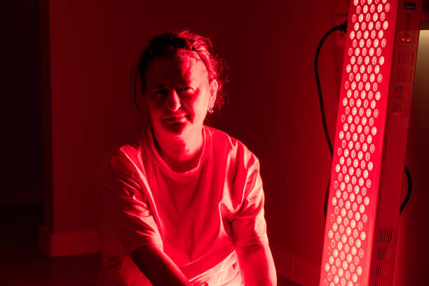 istock Elderly woman seated under red light therapy panel session 2193393083