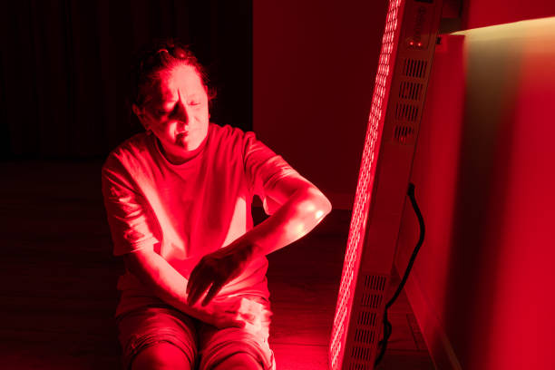 istock Focused view of elderly woman using red light therapy on her arm 2193393770