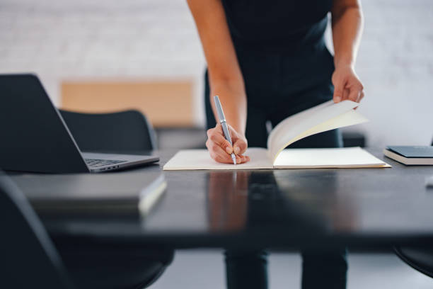 Person Writing on Paper at a Modern Office Desk