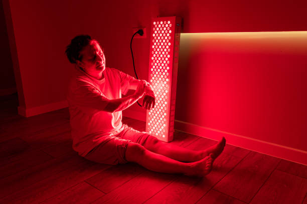 istock Elderly woman sitting on the floor under red light therapy panel 2193394155