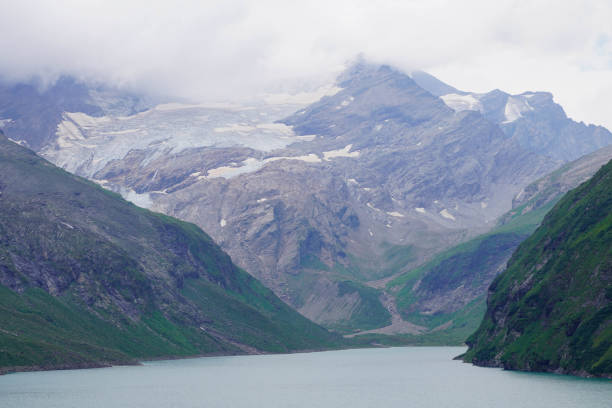 Kaprun high mountain reservoirs, Stausee Mooserboden coastline - cloudy summer day, August 20, 2024. Mountains, glacier, water reservoir  under the rainy cloudy sky but nice view before the storm.
