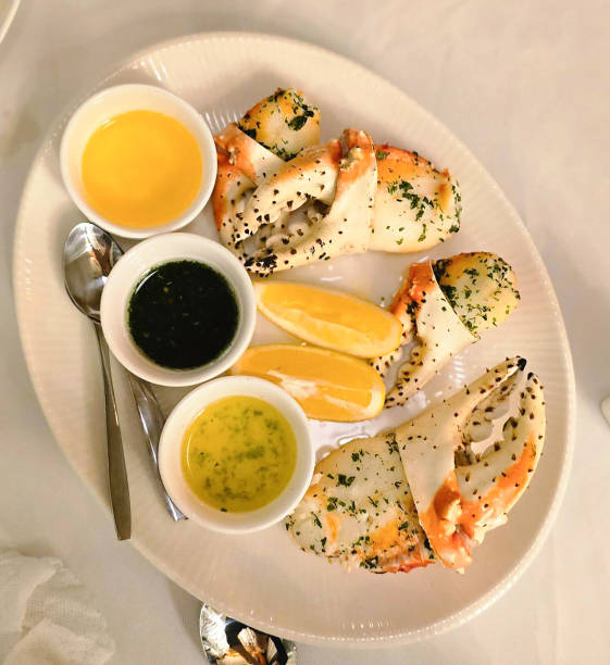 Golden pepper patties artfully arranged on a white fan-shaped platter, adorned with crab shells. Topped with tender diced crab meat, drizzled with golden pepper sauce, and garnished with white sesame seeds and fresh green herbs.