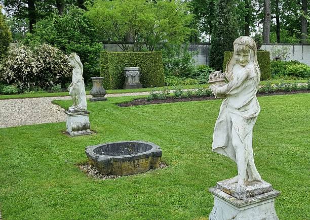 Spring garden exterior with clay pot - fresh green lawn, ornamental trees, shrubs and flowers. Landscape design concept.