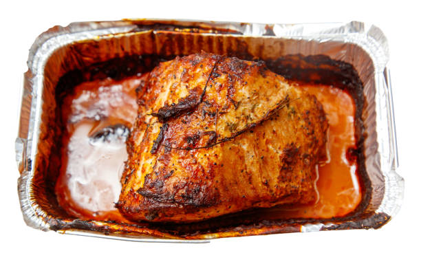 A piece of meat is cooked and sitting in a pan. The pan is covered with foil. The meat is browned and has a crispy texture