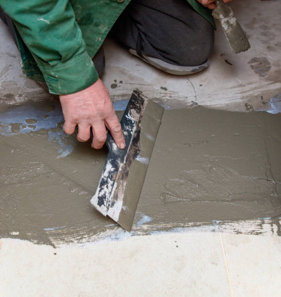 istock A man is laying on the floor and using a trowel to spread cement 2193407571