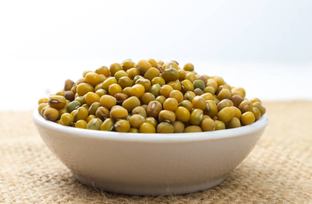 A close-up shot of a bowl filled with mung beans. The beans are yellow and green.