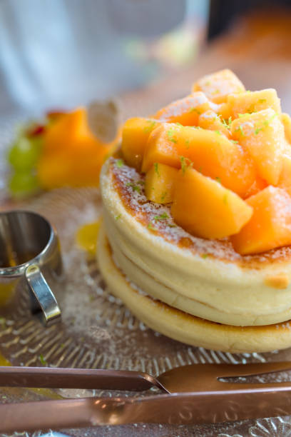 Mango pancakes are served with fresh fruit and syrup