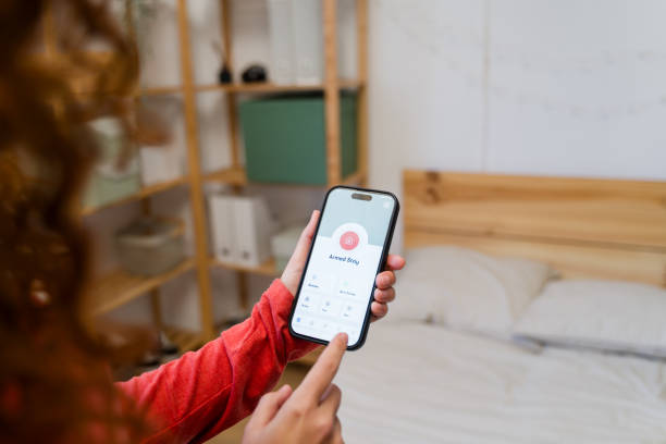 istock Woman arming home security system with smartphone app in bedroom 2193413812