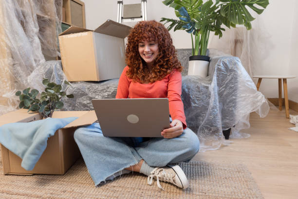 istock Young woman using laptop while moving into new apartment 2193414092