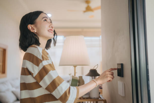 A modern woman is controlling lights on and off with an app on a digital tablet at her modern home at Bangkok, Thailand