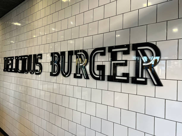 istock Black illuminated Delicious Burger sign on white tiled wall background 2193417912