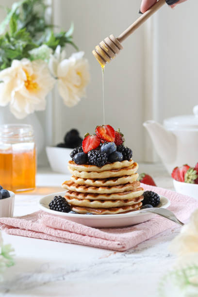 istock Stacked pancakes topped with fresh berries and honey drizzle in a cozy kitchen setting 2193418958