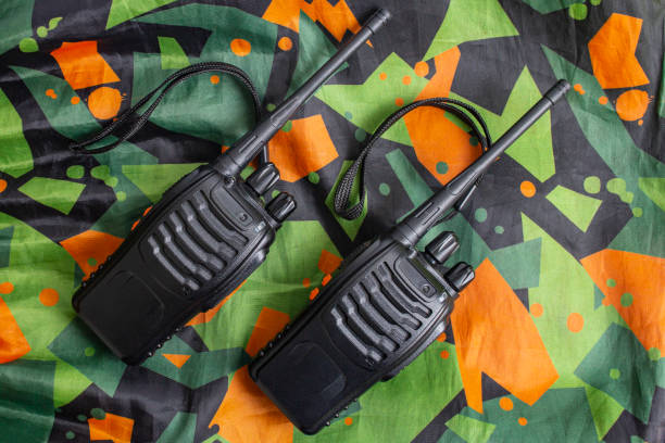 two walkie talkies on camouflaged fabric with green and orange pattern, flat lay