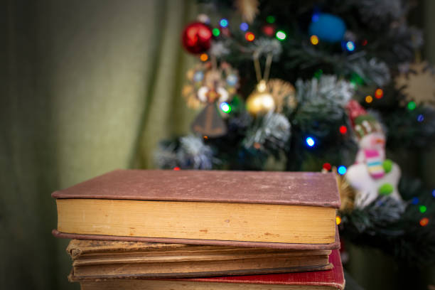istock Hard cover books stacked in front of a defocused christmas tree, abstract library backdrop 2193421545