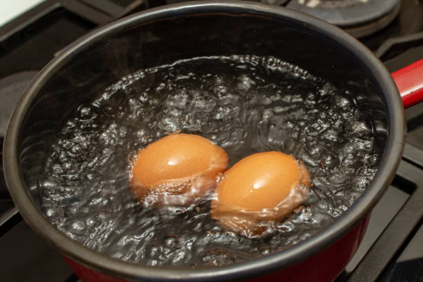 istock Two orange eggs boiling in a  black pot with bubbles and steam, soft focus  close up 2193421554